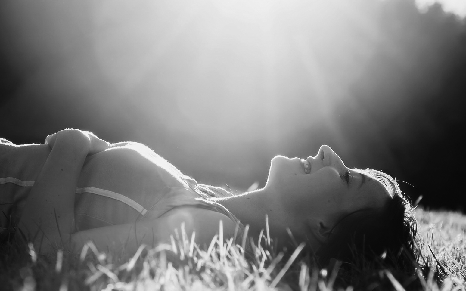 Young pretty woman lying on the grass at summer sunset. Natural