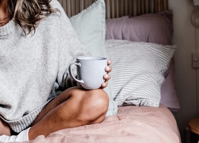 Rachel Claire/Unsplash https://www.pexels.com/photo/woman-sitting-on-a-bed-with-a-cup-of-tea-8113025/